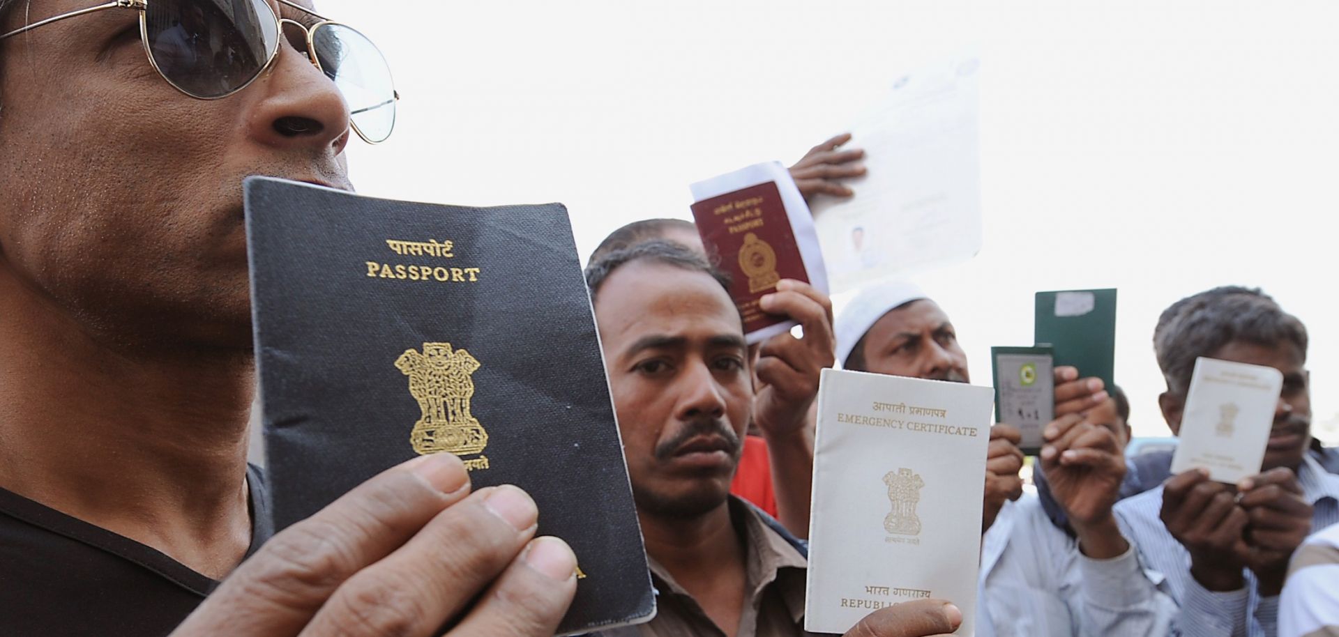 Foreign workers show their passports as they gather outside a Saudi immigration office in Riyadh, Saudi Arabia, on Nov. 4, 2013. 
