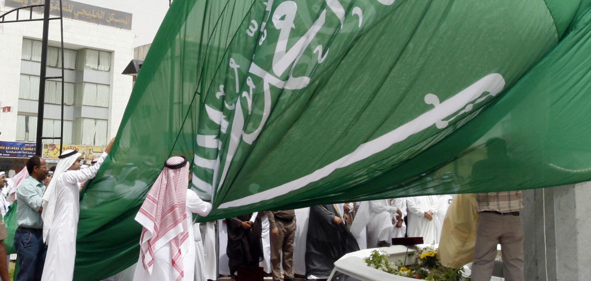 Saudi men unfurl a giant Saudi national flag during a ceremony to raise the highest flag in the country in the eastern city of Dammam on June 17, 2008.