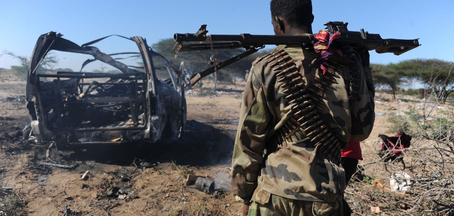 A soldier walks past the wrecked car that suicide bombers filled with explosives.