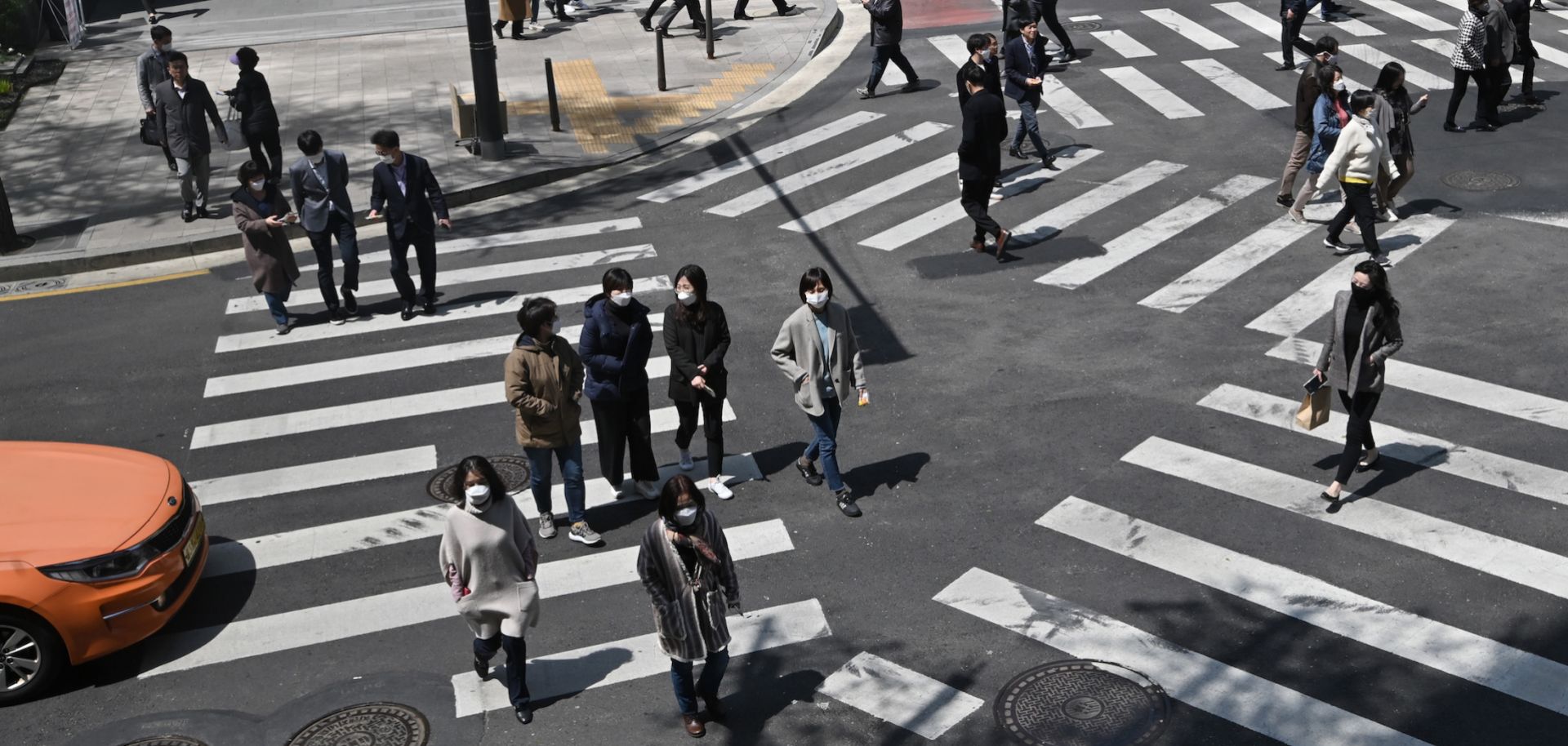Pedestrians wearing face masks cross an intersection in Seoul, South Korea, on April 23, 2020. In the first quarter of 2020, South Korea's economy saw its worst performance in more than a decade as COVID-19 spread across the country. 