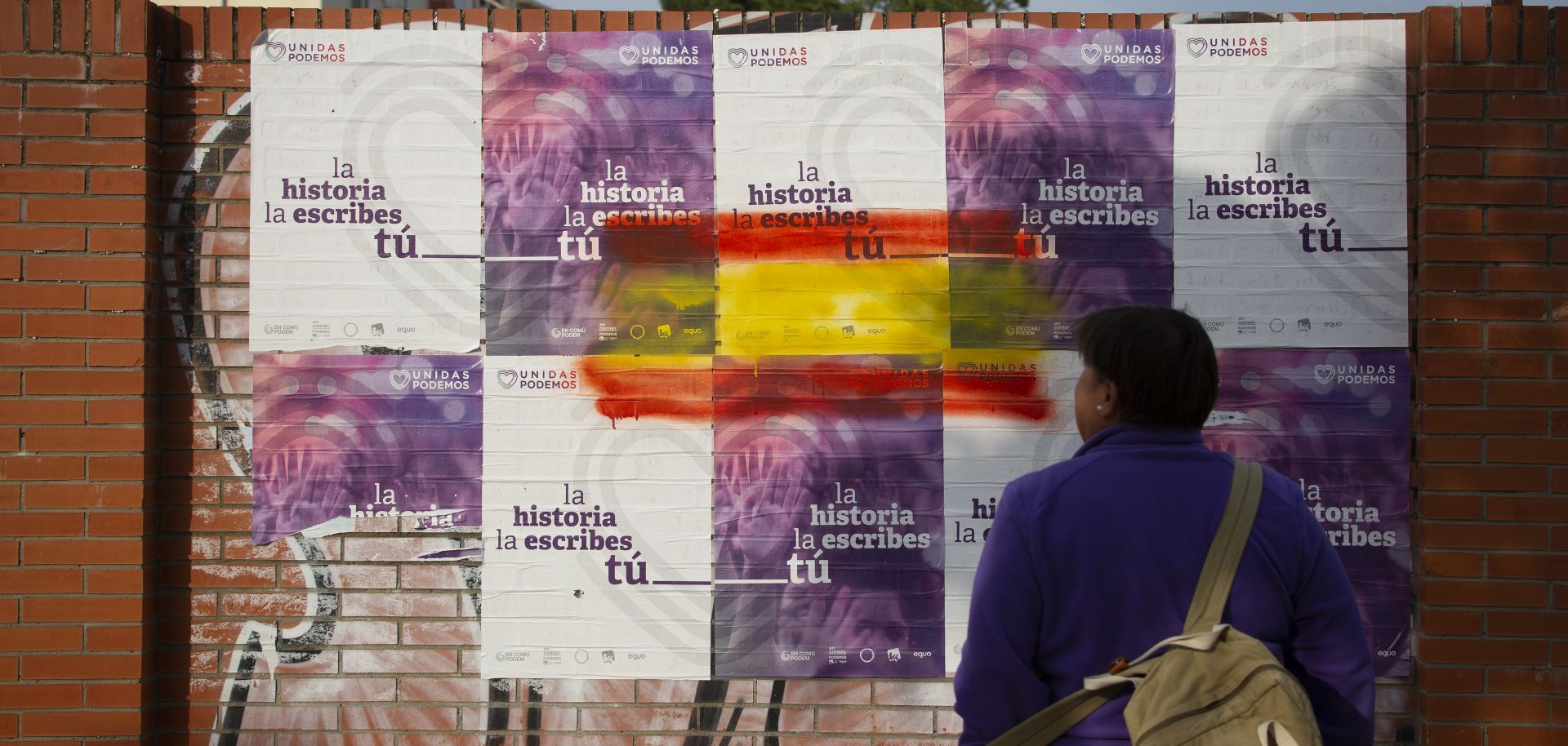 A woman in Seville, Spain, looks at election posters for the United We Can (Unidas Podemos) party on April 22, 2019.