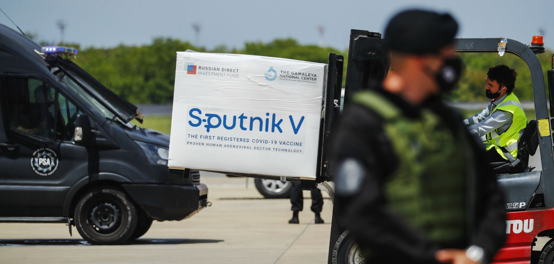 A member of the airport police stands guard as a forklift unloads a container full of Russia’s Sputnik V COVID-19 vaccine from a plane in Ezeiza, Argentina, on Jan. 16, 2021. 