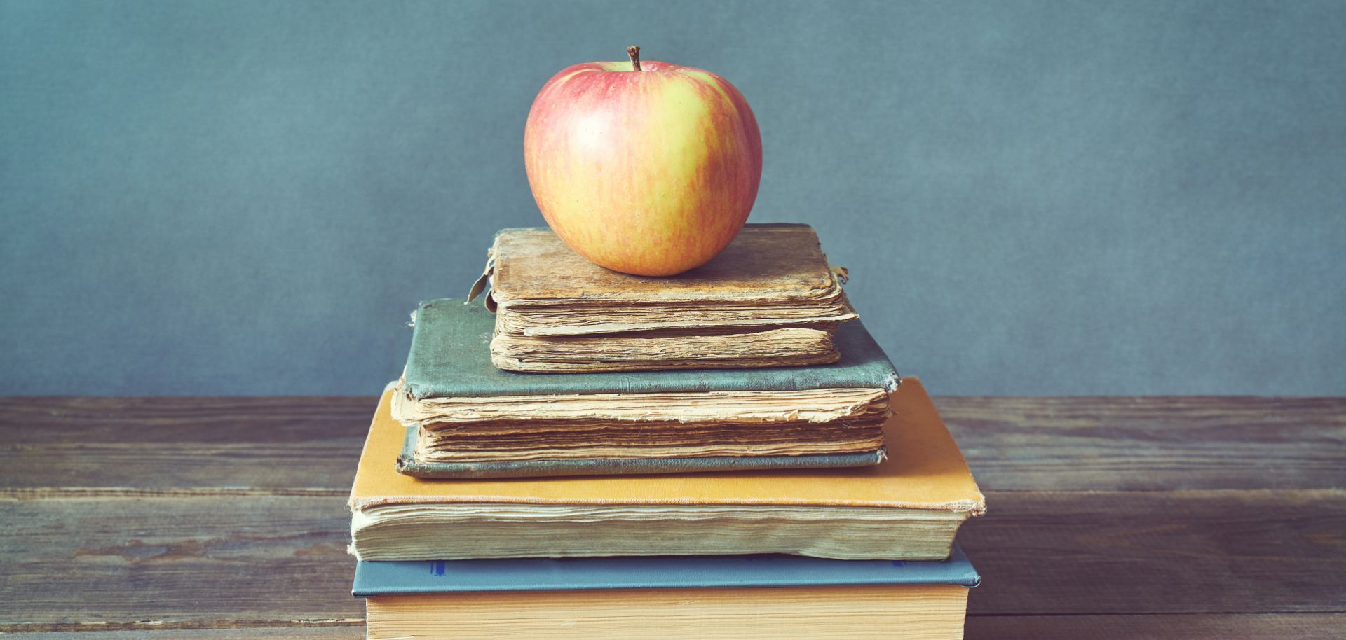 An apple sits atop a stack of books.