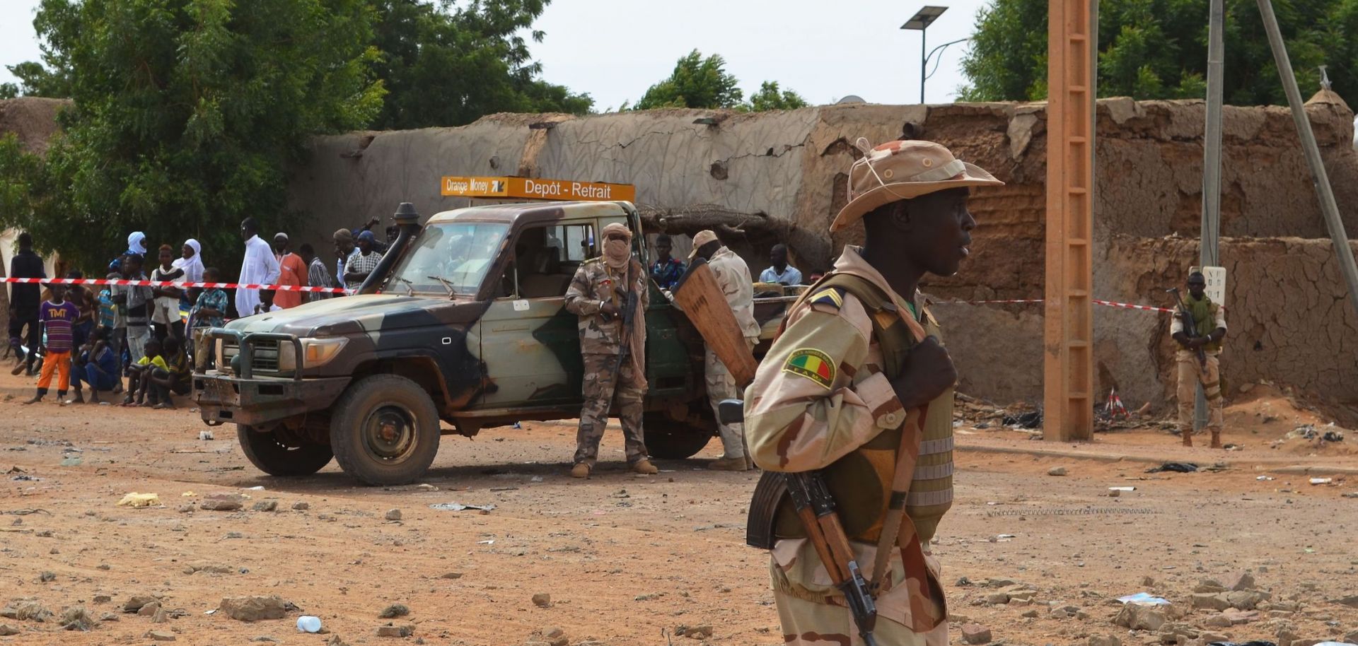 Malian soldiers stand beside a destroyed building