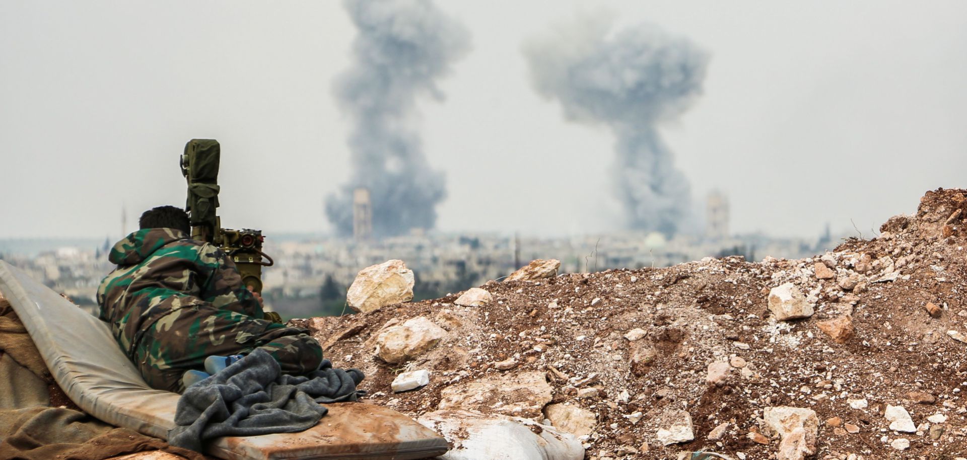 A Syrian government forces soldier observes artillery fire on April 1, 2017, near Qumhanah in the central province of Hama.