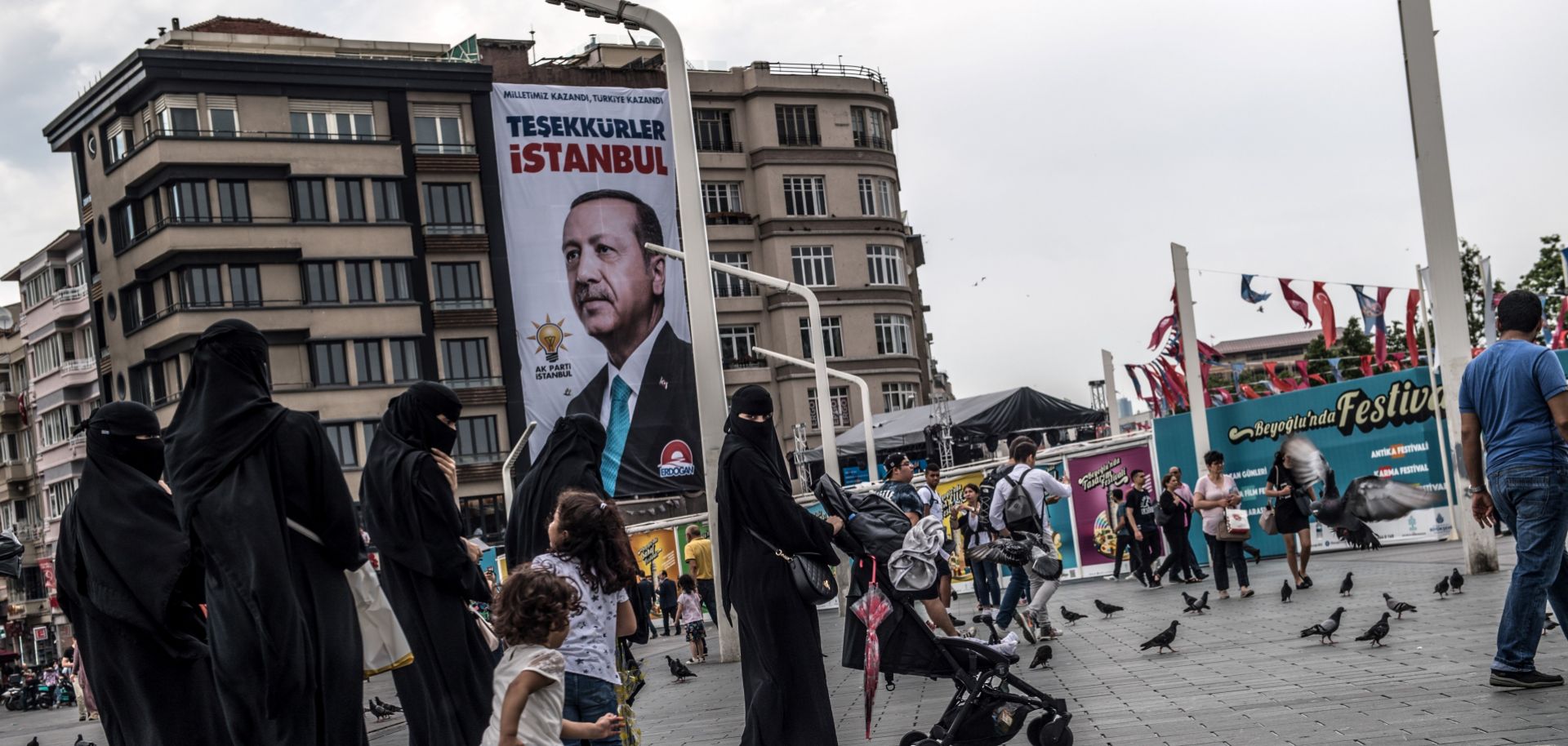 Pedestrians cross Taksim Square in Istanbul, June 28. The poster behind them shows Turkish President Recep Tayyip Erdogan with a message that read: "Thank you Istanbul."