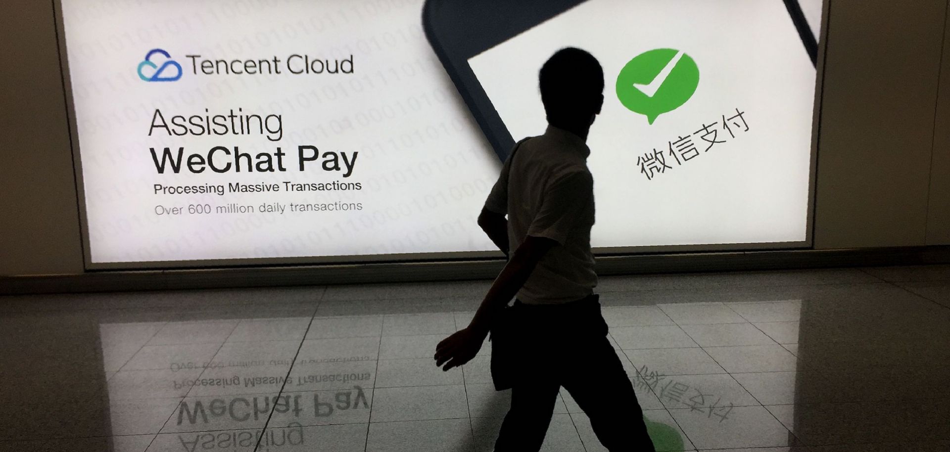 In this August 2017 photo, a man walks past an ad in Hong Kong's international airport for the social media platform WeChat, which is owned by China's Tencent.