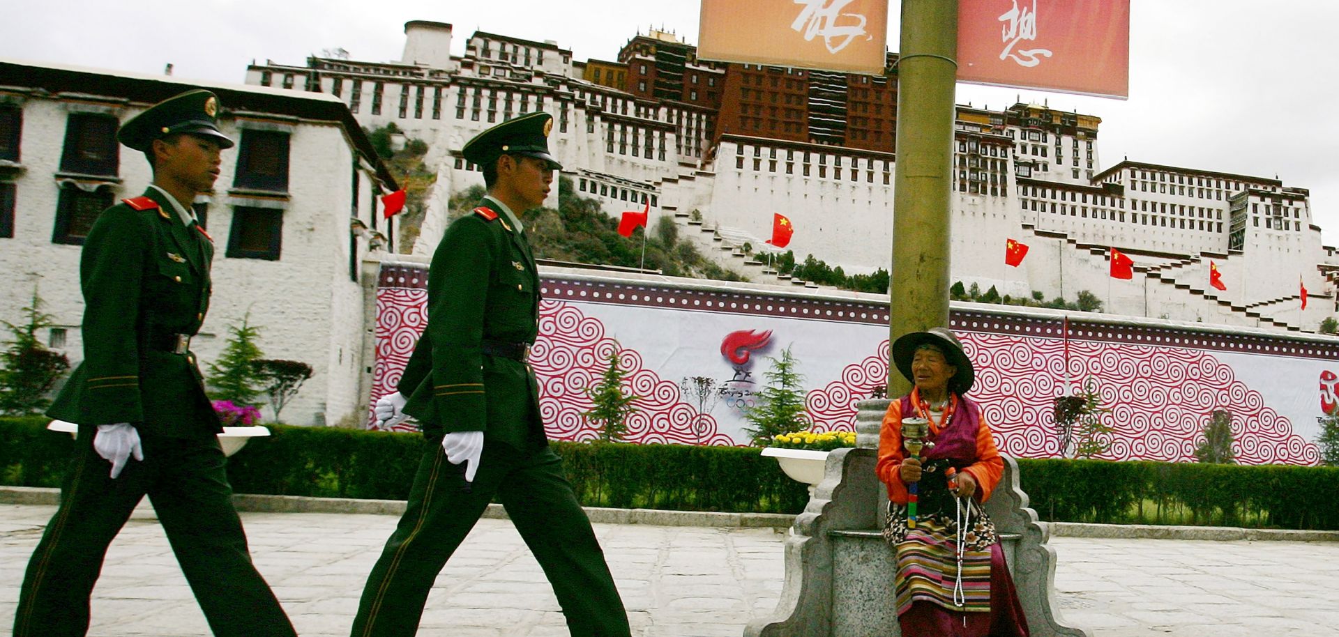 A Tibetan worshiper looks at Chinese police officer patrolling in front of Potala Palace in Lhasa, Tibet.