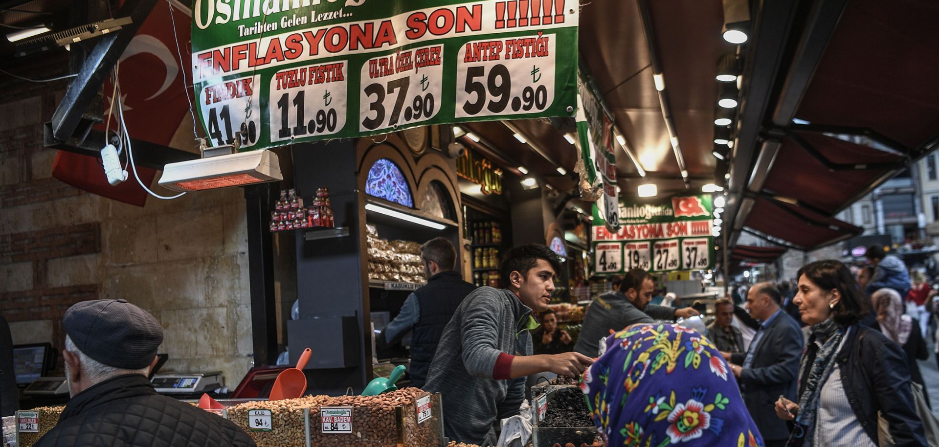Vendors sell nuts as people shop under a banner reading "An End to Inflation" in Istanbul's Eminonu neighborhood on Nov. 6, 2018.