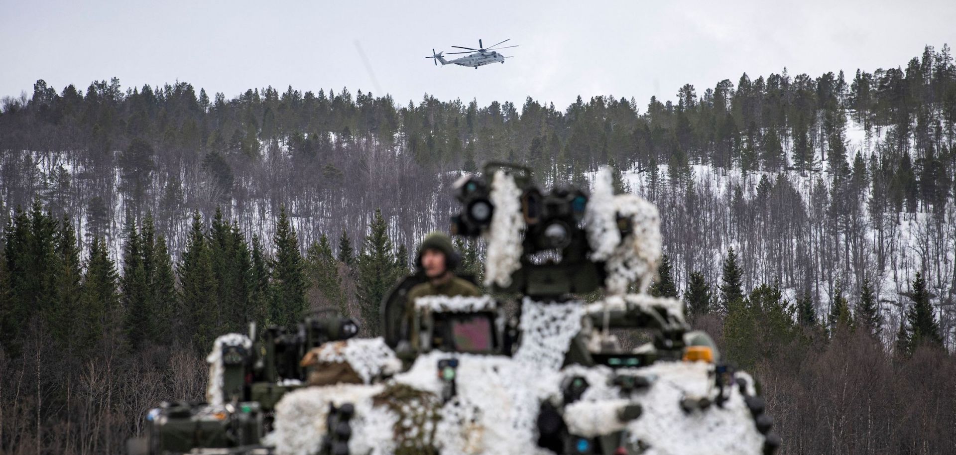 A heavy-lift helicopter operated by the U.S. military flies over a tank in Setermoen, Norway, during a military exercise involving NATO troops and partner countries on March 22, 2022. 