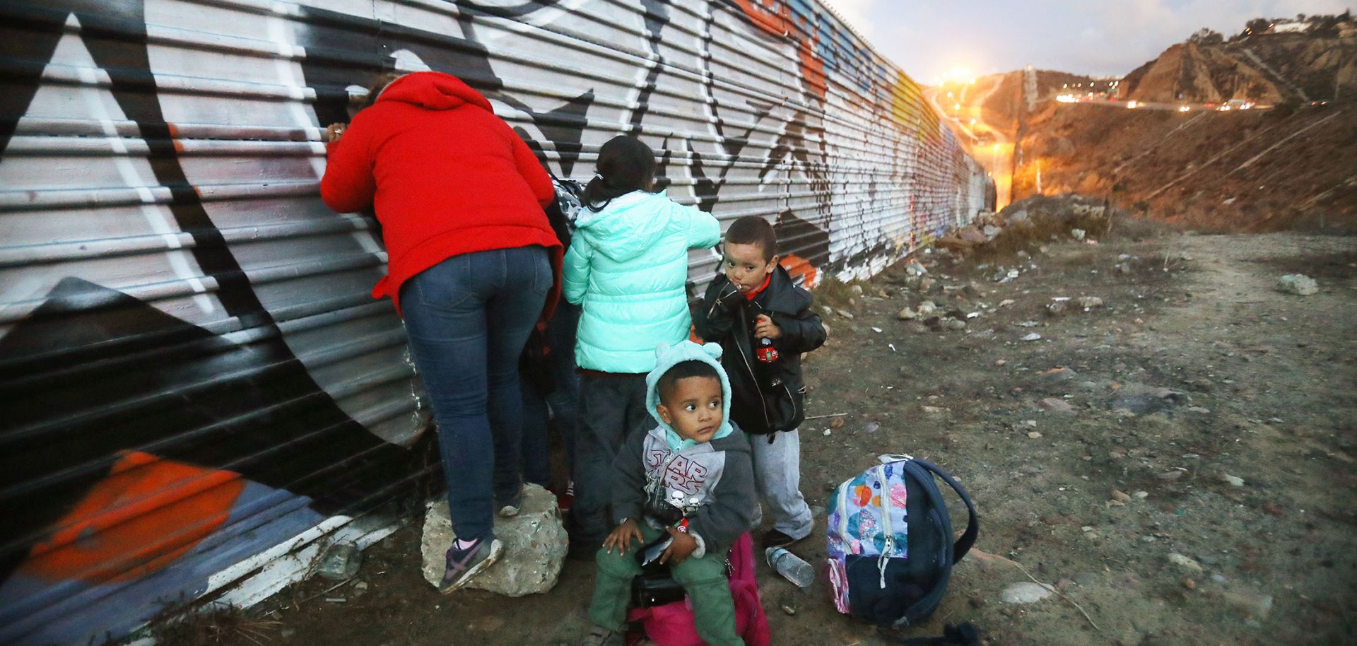 A picture showing Honduran migrants gathering on the Mexican side of the U.S.-Mexico border fence near Tijuana after unsuccessfully attempting to cross into the United States, Dec 1. 