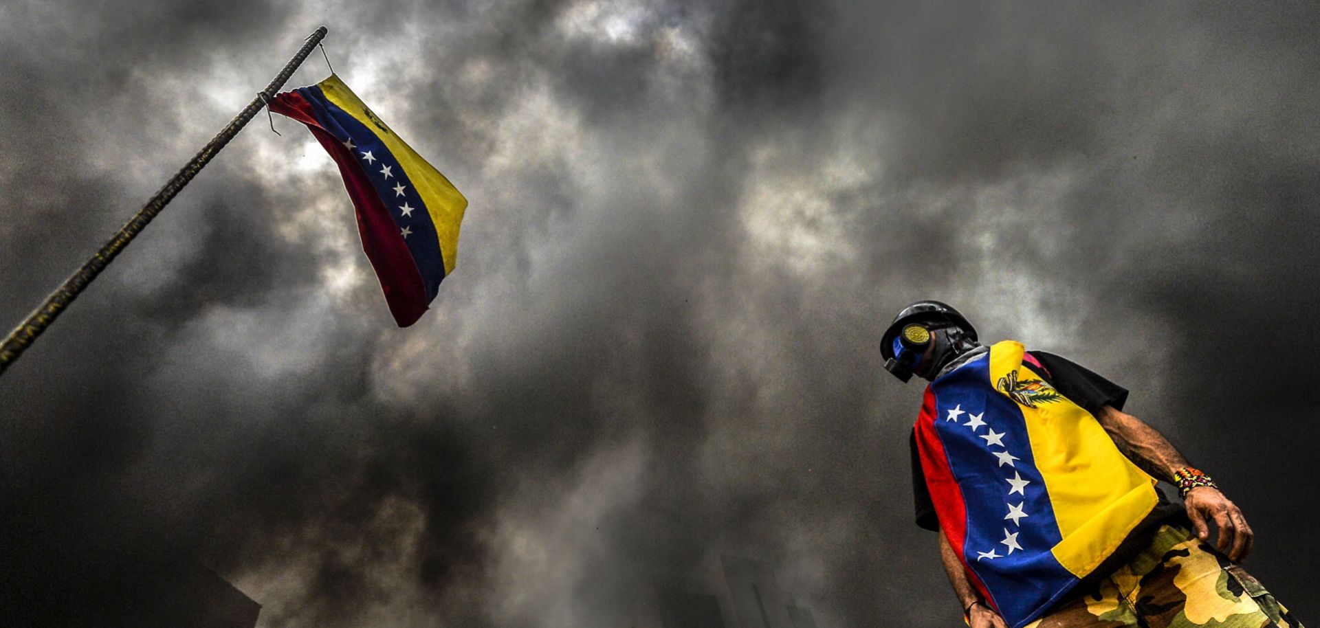 An anti-government demonstrator stands next to the Venezuelan national flag during an opposition protest blocking the Francisco Fajardo highway in Caracas in May.