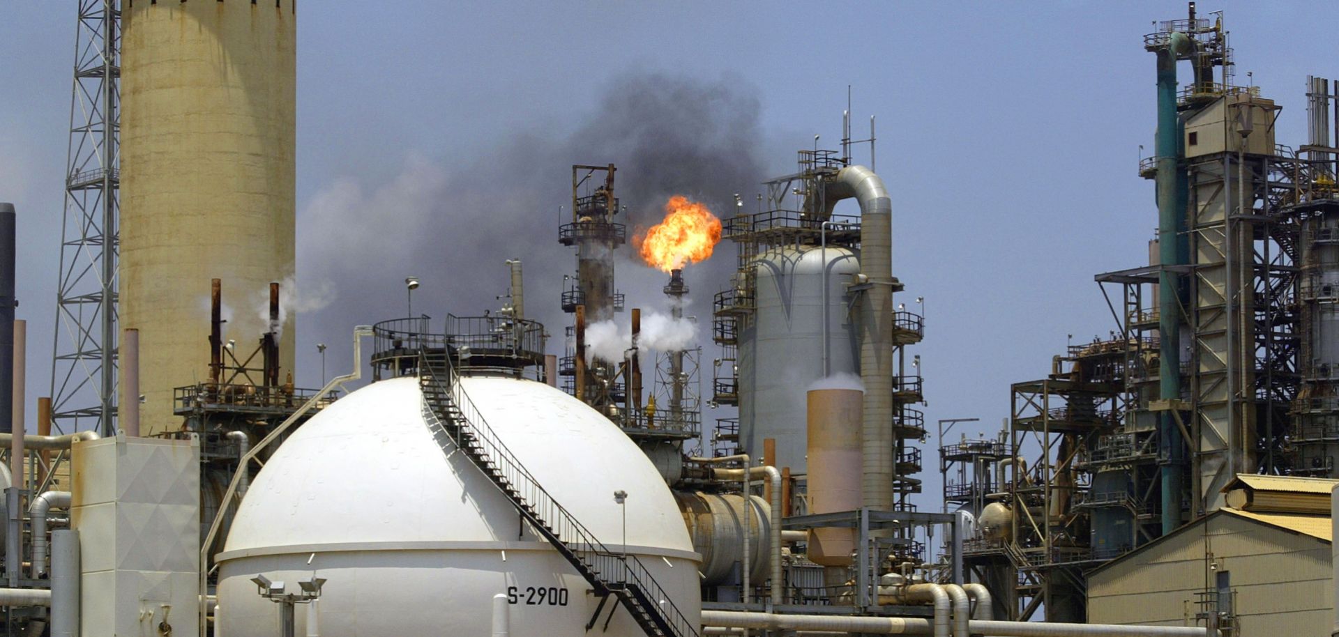 A controlled flame burns behind a storage tank at an oil refinery complex in Venezuela.