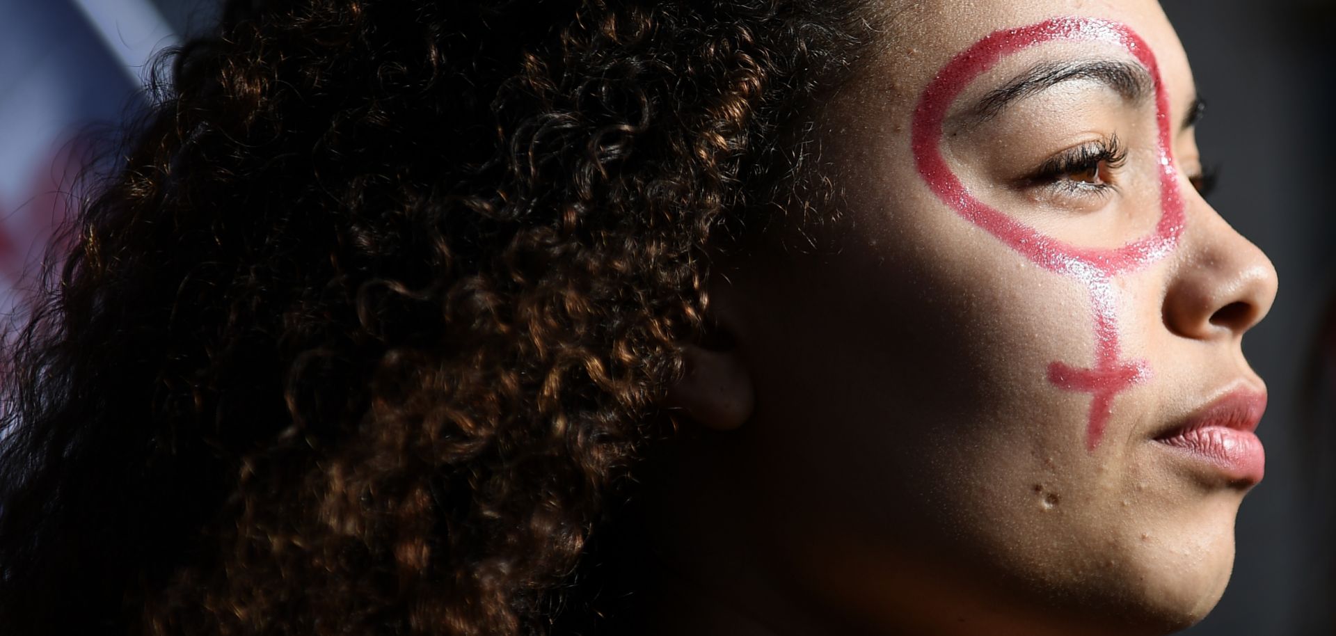 A woman with the female gender pictogram made up on her face attends a demonstration as part of the 40th International Women's Day on March 8, 2017 in Marseille.