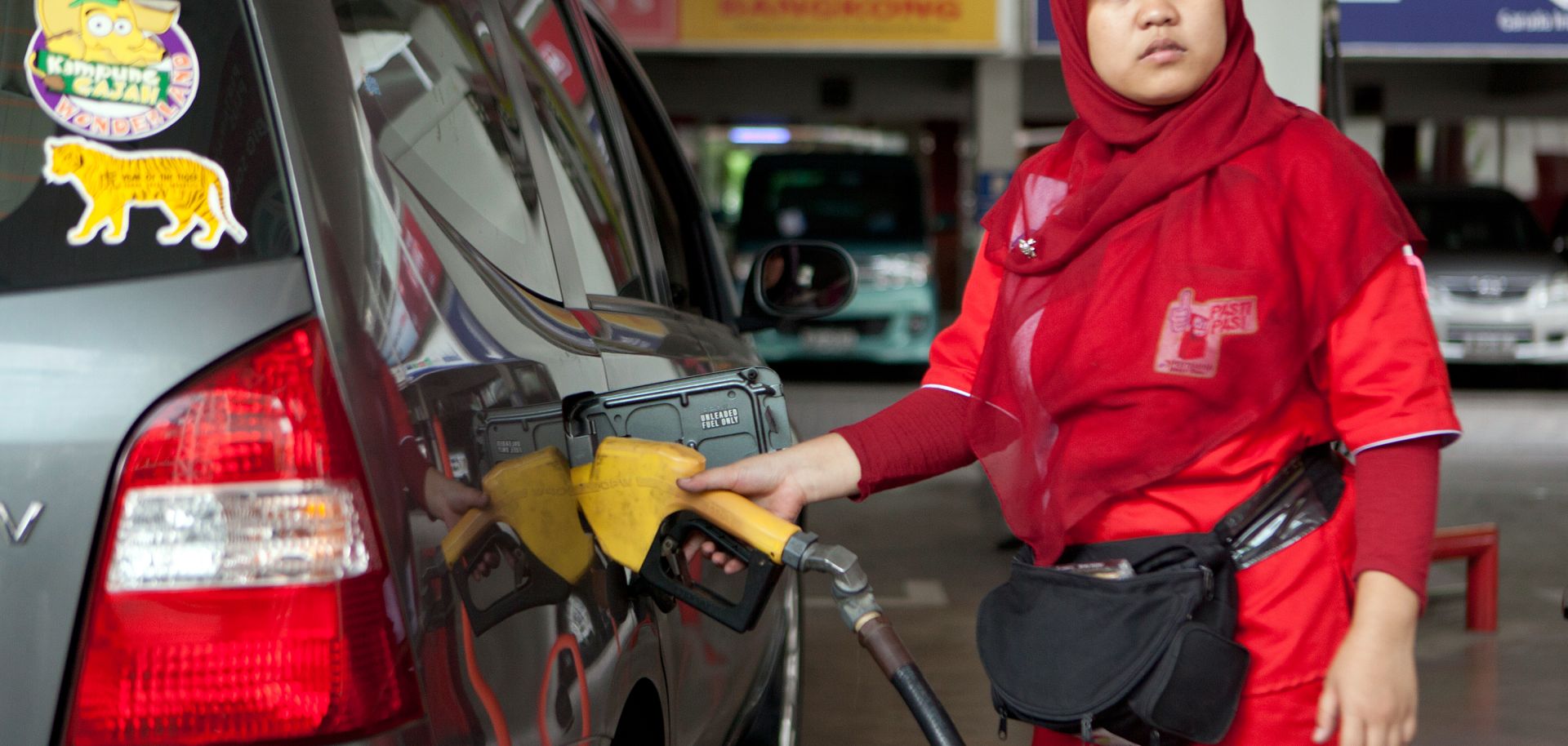 A service station worker fills up a customer's tank at a petrol station in Jakarta.