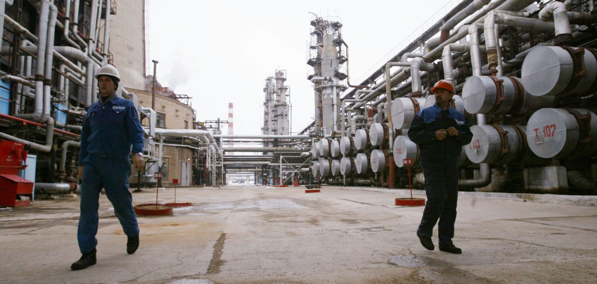Workers walk through an oil refinery.