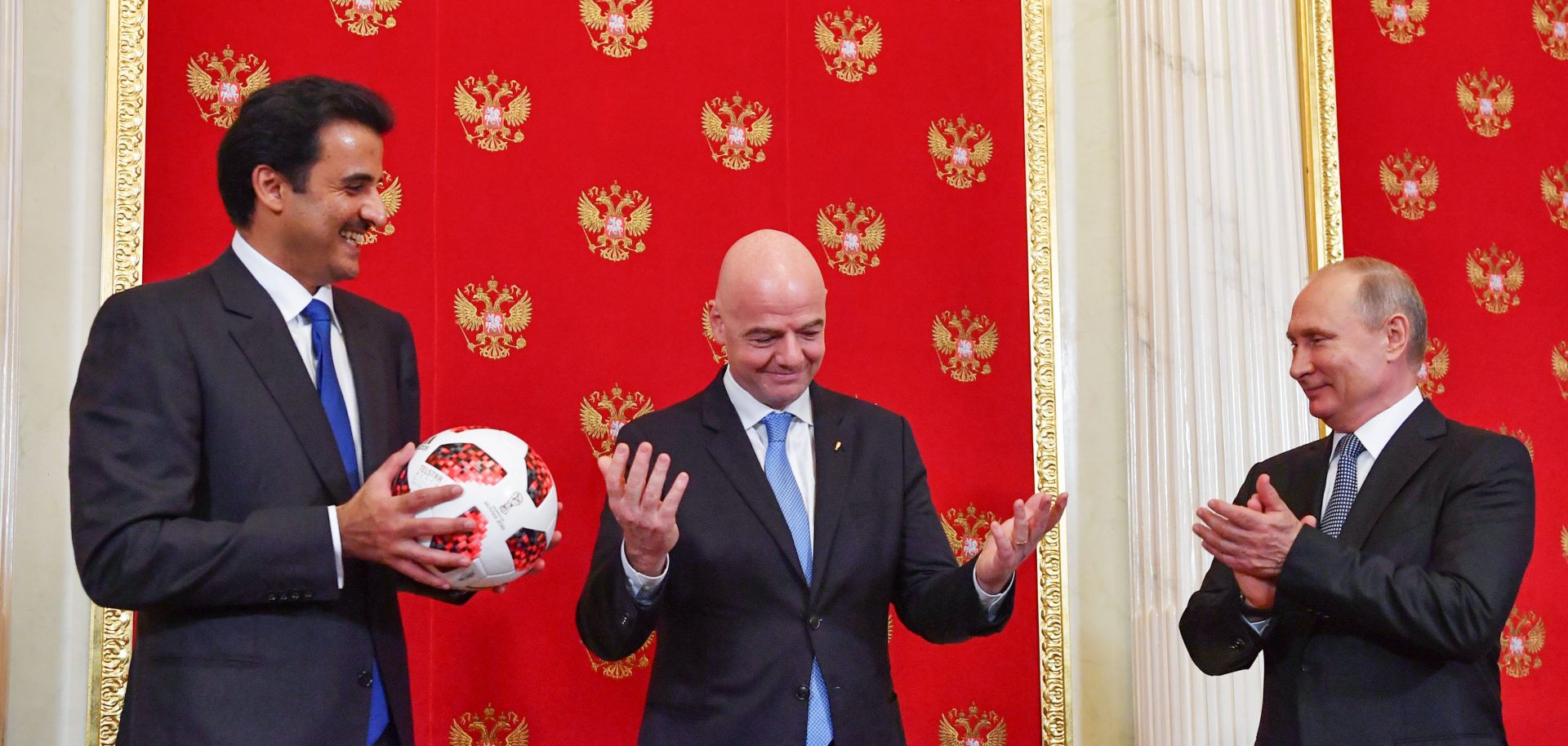 Qatari Emir Sheikh Tamim bin Hamad al-Thani (L) smiles at FIFA President Gianni Infantino (C) and Russian President Vladimir Putin at the end of the 2018 World Cup in Russia. As part of the closing ceremony, Putin passed a soccer ball to al-Thani, whose country will hold the next tournament in 2022, in a symbolic gesture.