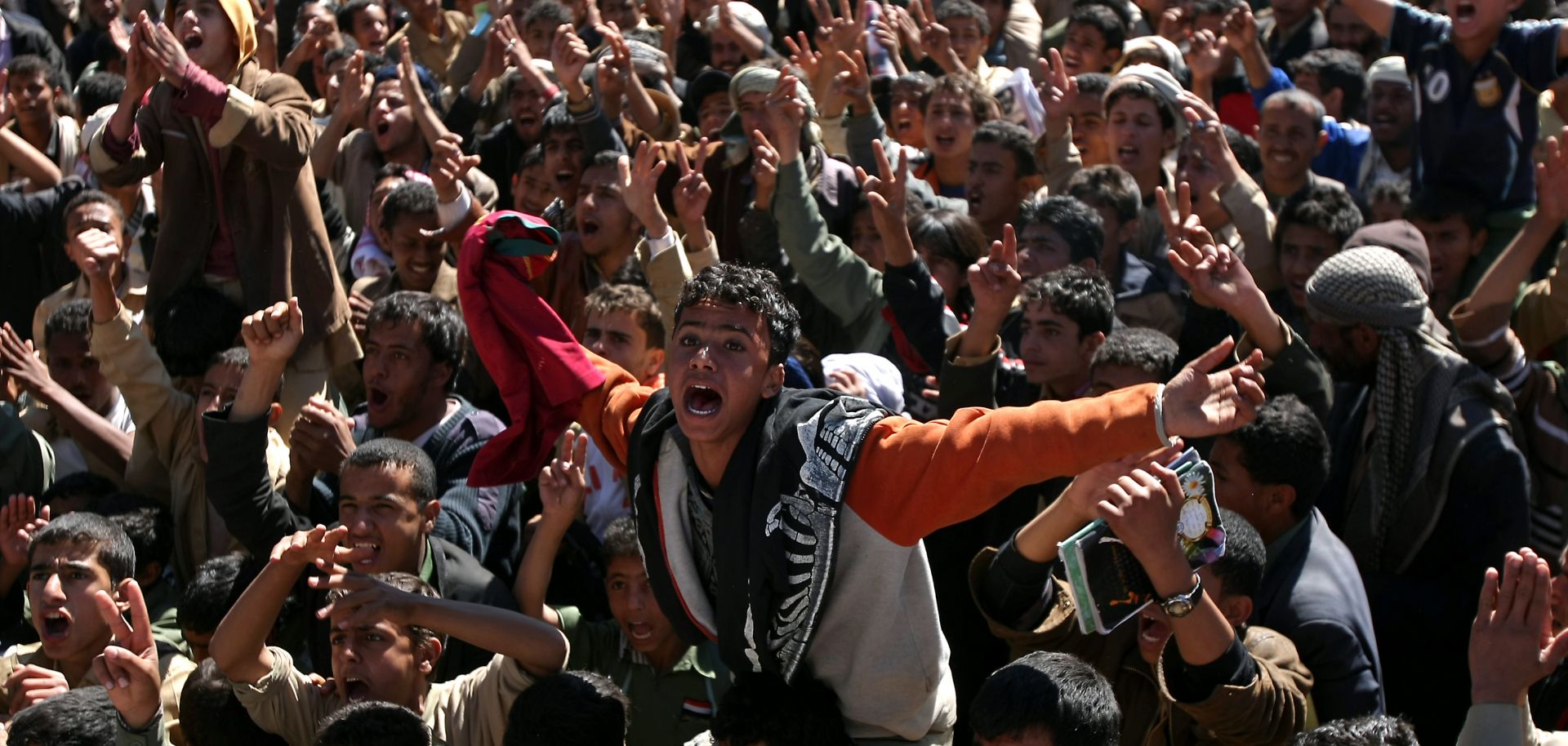 Protestors gather in Yemen, chanting and holding signs.