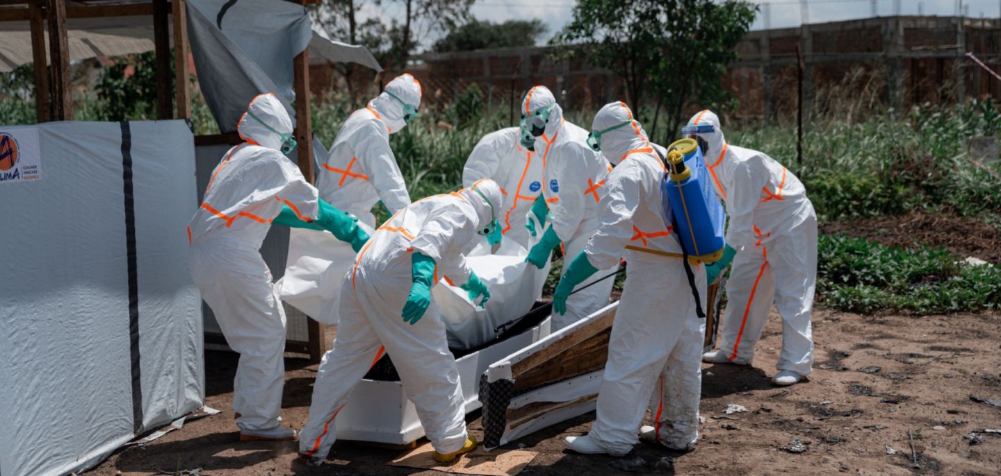 Red Cross volunteers wearing personal protective equipment lower the body of an Ebola victim into a casket at a health center in Ituri province, Democratic Republic of Congo, on June 8, 2026.