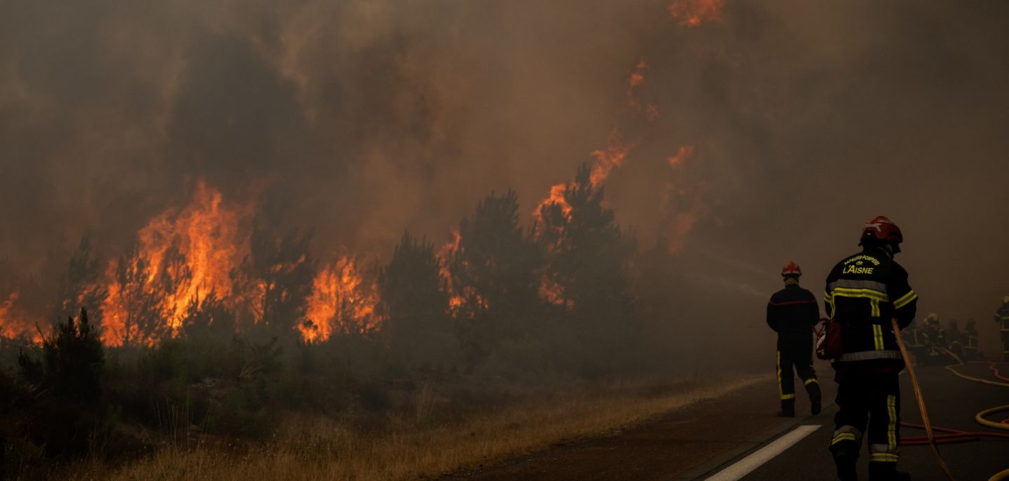 Firefighters spray water along the edge of a forest during a wildfire in southwestern France on July 25, 2026. 