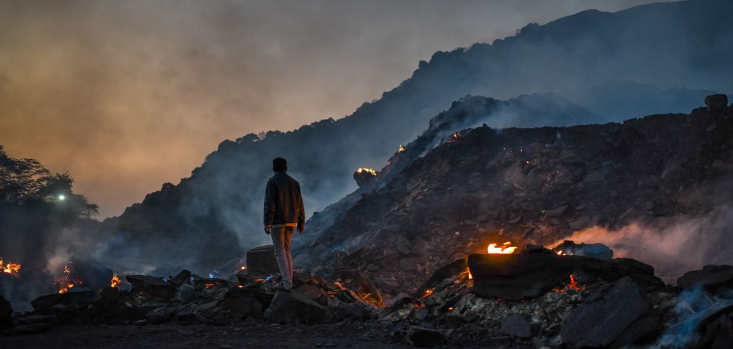 A man stands near burning waste at a coal mine in Sonbhadra, India, on Nov. 22, 2021. High oil and gas prices amid the war in Ukraine risks making India, the world’s second-largest coal consumer, even more reliant on the cheapest (and dirtiest) fossil fuel.