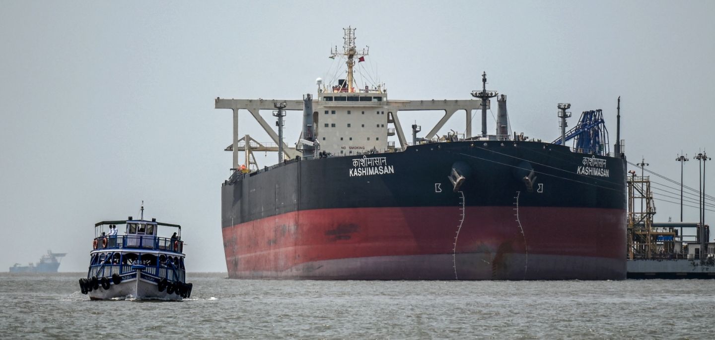 A passenger boat sails past the Indian-flagged oil tanker Kashimasan, which is docked near an offloading terminal at Butcher Island (also known as Jawahar Dweep) off the coast of Mumbai, India, on April 1, 2026.