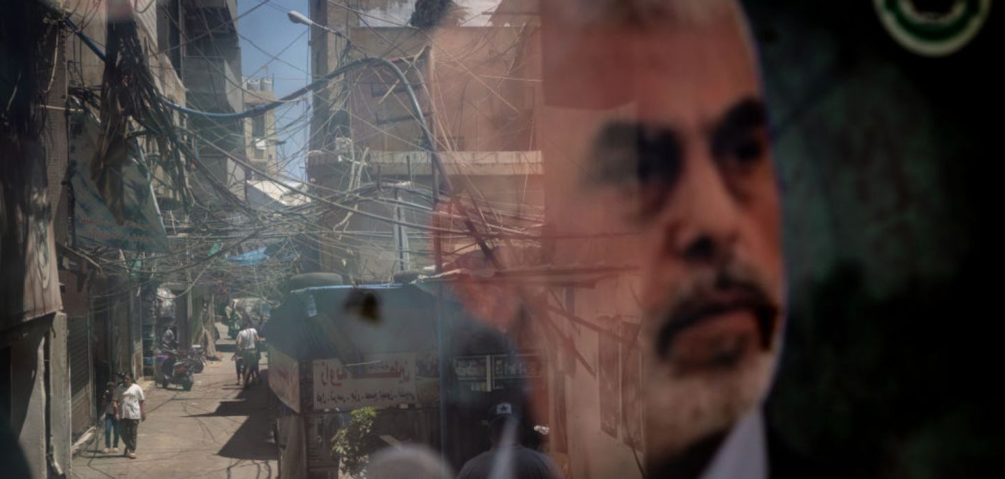 People are reflected in a window displaying a poster of Hamas leader Yahya Sinwar in the Palestinian camp of Bourj al-Barajneh on Aug. 8, 2024, in Beirut, Lebanon. 