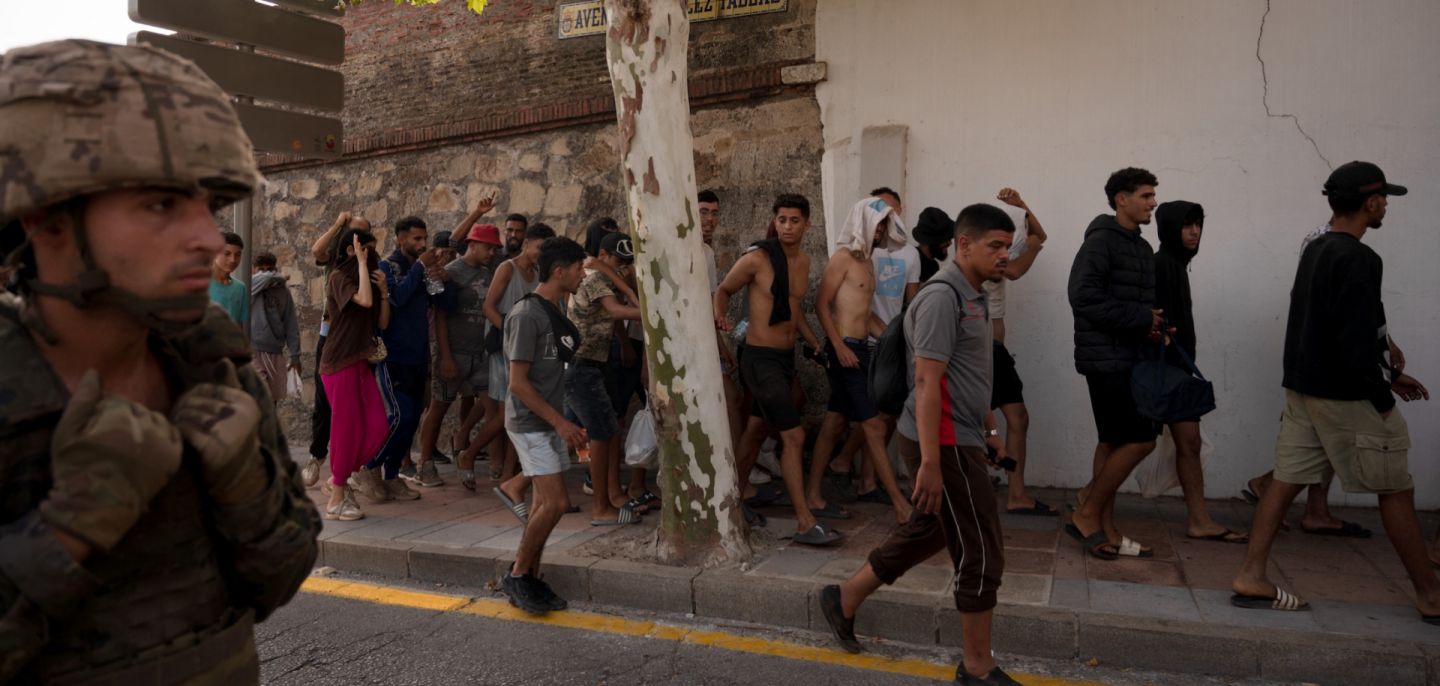 A Spanish soldier escorts a group of migrants on their way back towards the Moroccan border, following their illegal crossing into the Spanish enclave of Ceuta, on Aug. 1, 2026.