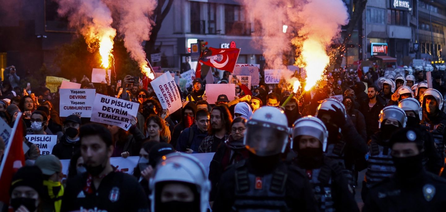 Escorted by riot police, students burn flares on March 24, 2025, as they march along the streets of Istanbul, Turkey, in support of the city's mayor after he was arrested on corruption charges. 