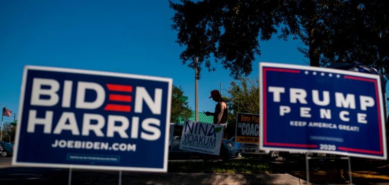 Biden and Trump campaign signs are displayed as voters line up to cast their ballots during early voting Oct. 30, 2020, at the Alafaya Branch Library in Orlando, Florida. 