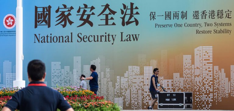 Technicians in Hong Kong walk next to a banner supporting China’s new national security law following a flag-raising ceremony marking the 23rd anniversary of the city’s British handover on July 1, 2020. Technicians in Hong Kong walk next to a banner supporting China’s new national security law following a flag-raising ceremony marking the 23rd anniversary of the city’s British handover on July 1, 2020.