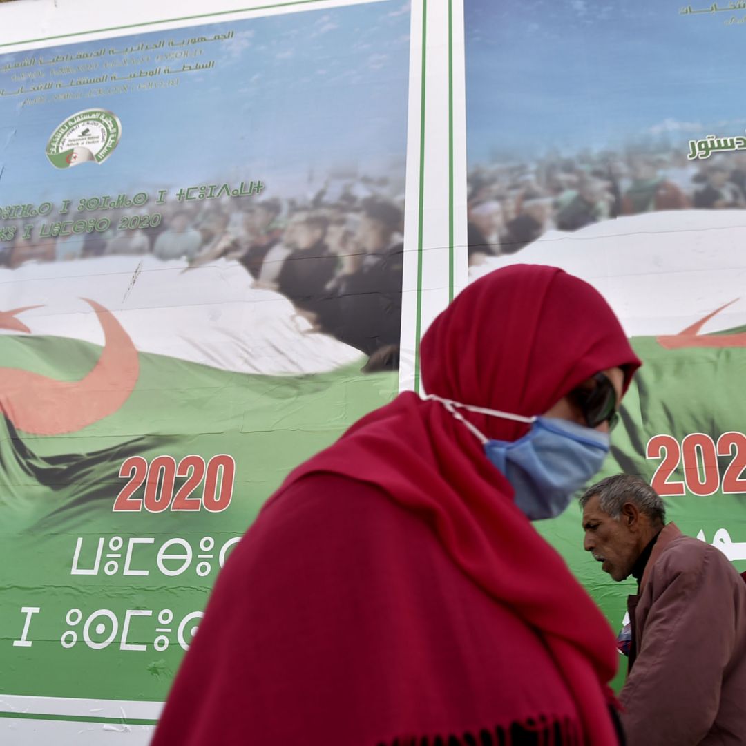 People walk past campaign billboards ahead of the upcoming constitutional referendum on a street in Algiers, Algeria, on Oct. 22, 2020. 