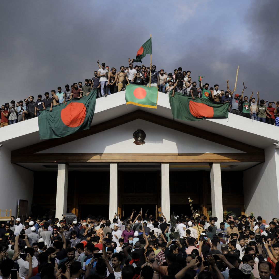 Anti-government protesters display Bangladesh's national flag as they storm Prime Minister Sheikh Hasina's palace in Dhaka on Aug. 5, 2024.