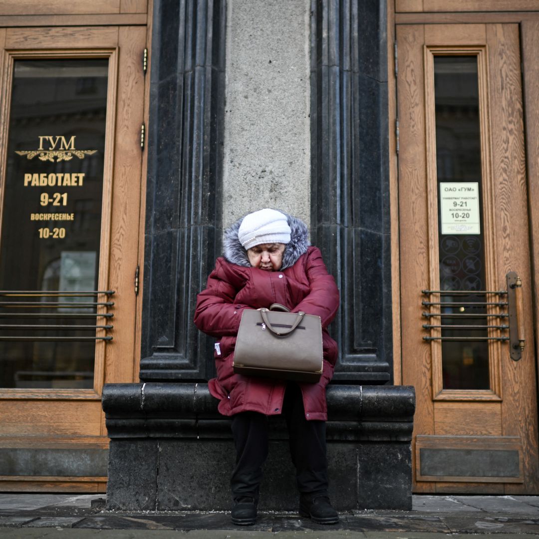 A woman sits by the entrance to the GUM department store in central Minsk on February 14, 2023.