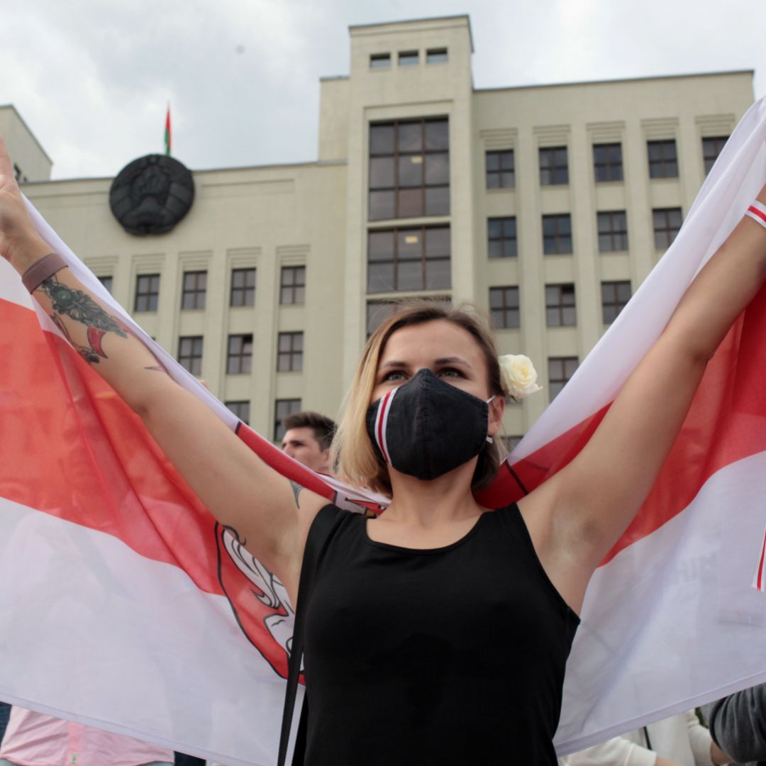 A woman wearing a face mask holds the former flag of Belarus at an anti-government protest in Minsk on Aug. 14, 2020. 