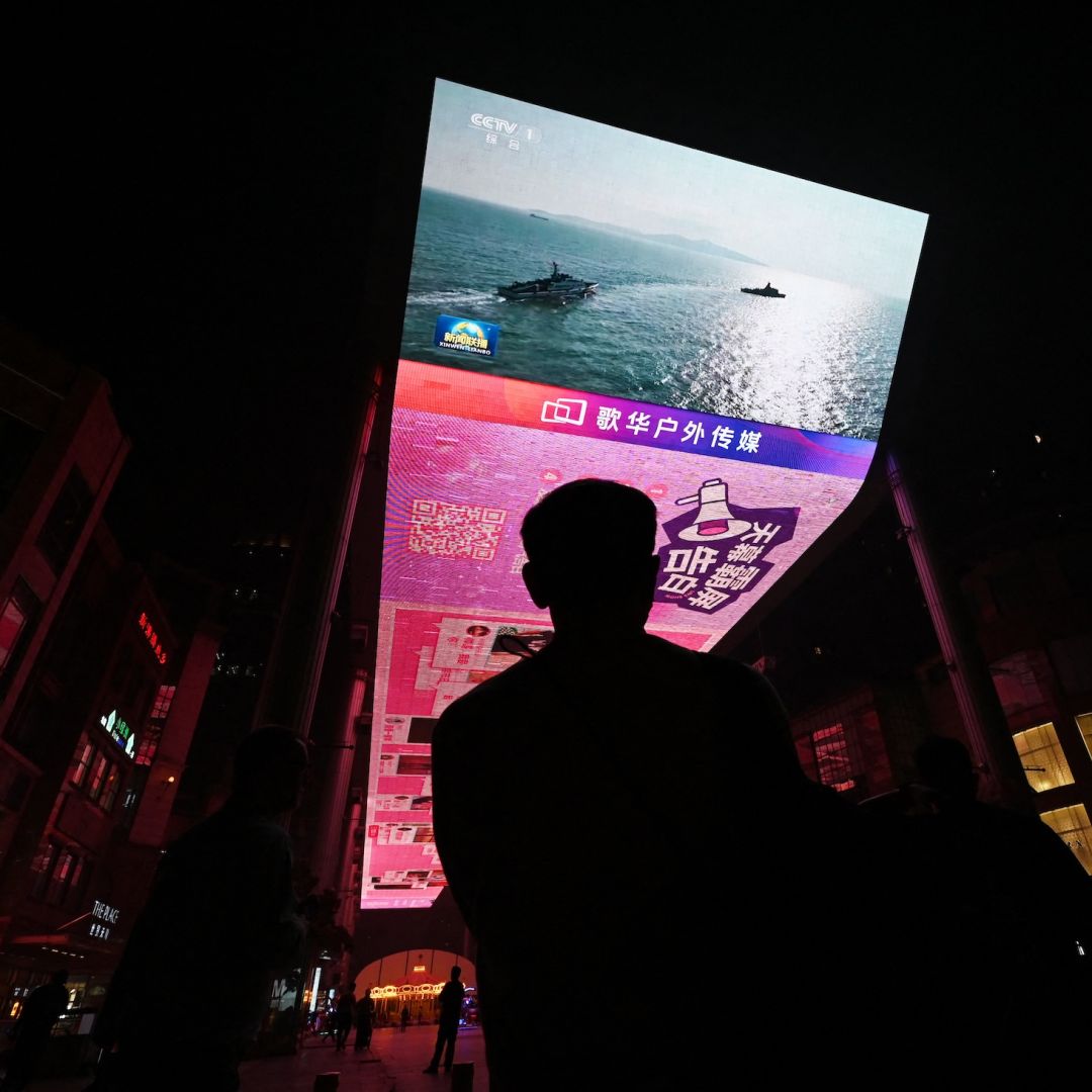 A man watches a news program about Chinese military drills surrounding Taiwan on a giant screen outside a shopping mall in Beijing on Oct. 14, 2024.