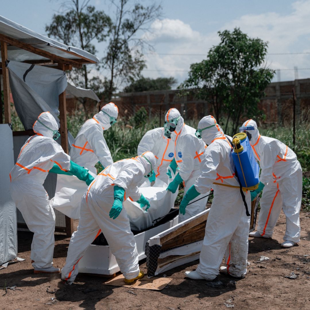 Red Cross volunteers wearing personal protective equipment lower the body of an Ebola victim into a casket at a health center in Ituri province, Democratic Republic of Congo, on June 8, 2026.
