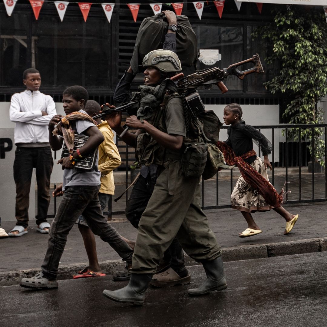 A member of the M23 armed group walks alongside residents through a neighborhood in Goma, eastern Congo, on Jan. 27, 2025. 