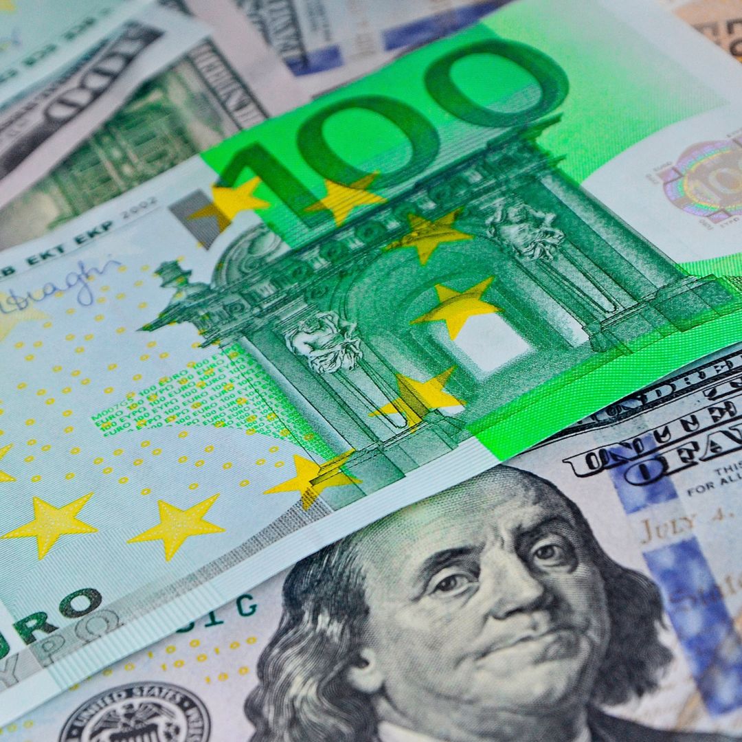 Euro banknotes lie atop U.S. dollar banknotes. Euro banknotes lie atop U.S. dollar banknotes.