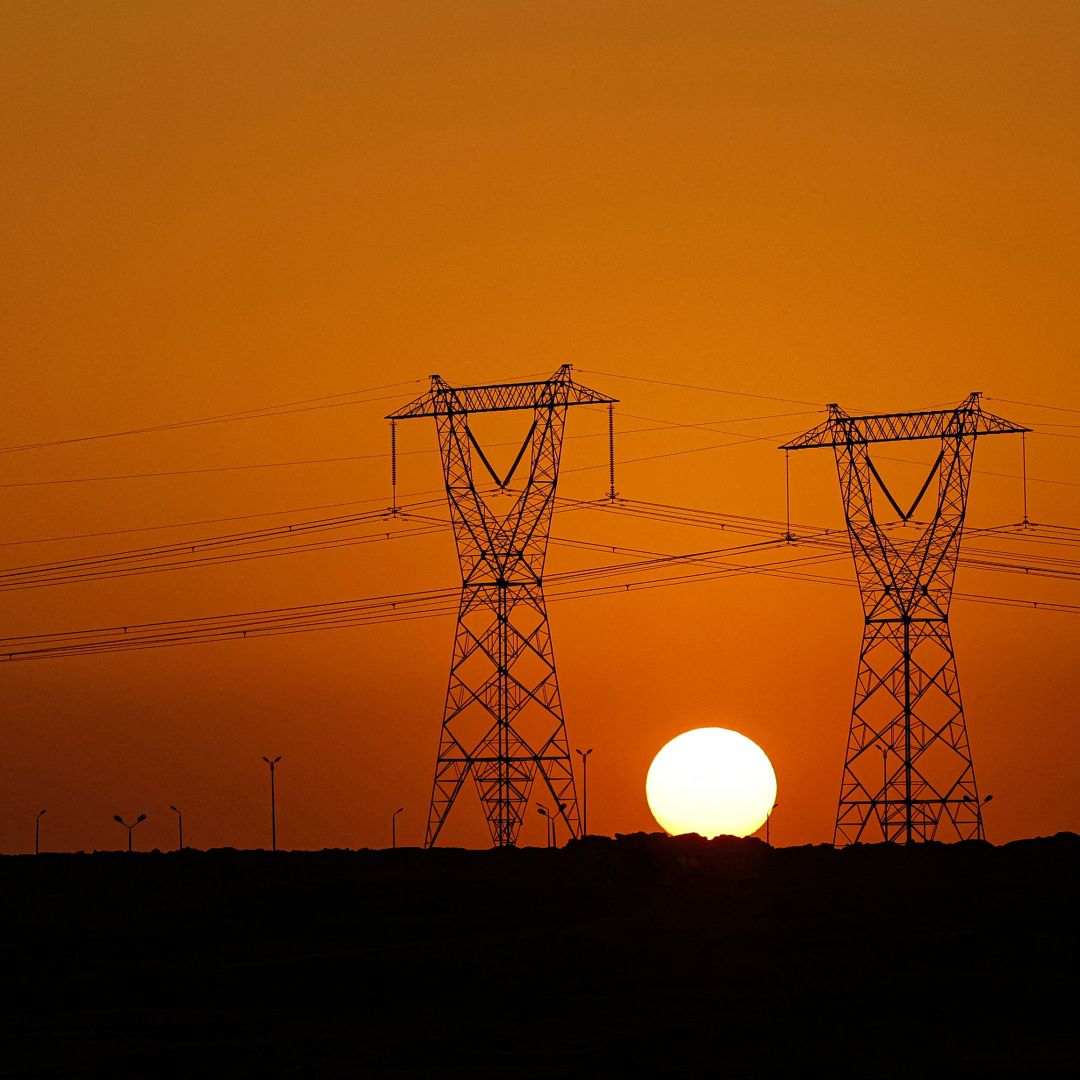 The sun sets behind high voltage transmission towers along a highway in El-Shorouk, about 47 kilometers outside the city center of Cairo, on July 24, 2023. 