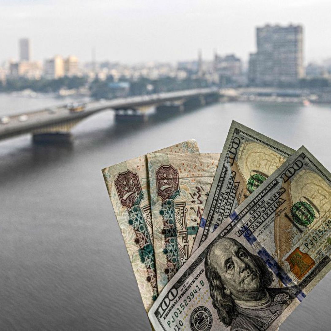 Two pairs of U.S. hundred dollar bills and Egyptian hundred pound notes are held before a window showing the skyline of Egypt's capital Cairo and the Nile River on Jan. 16, 2023. Two pairs of U.S. hundred dollar bills and Egyptian hundred pound notes are held before a window showing the skyline of Egypt's capital Cairo and the Nile River on Jan. 16, 2023.