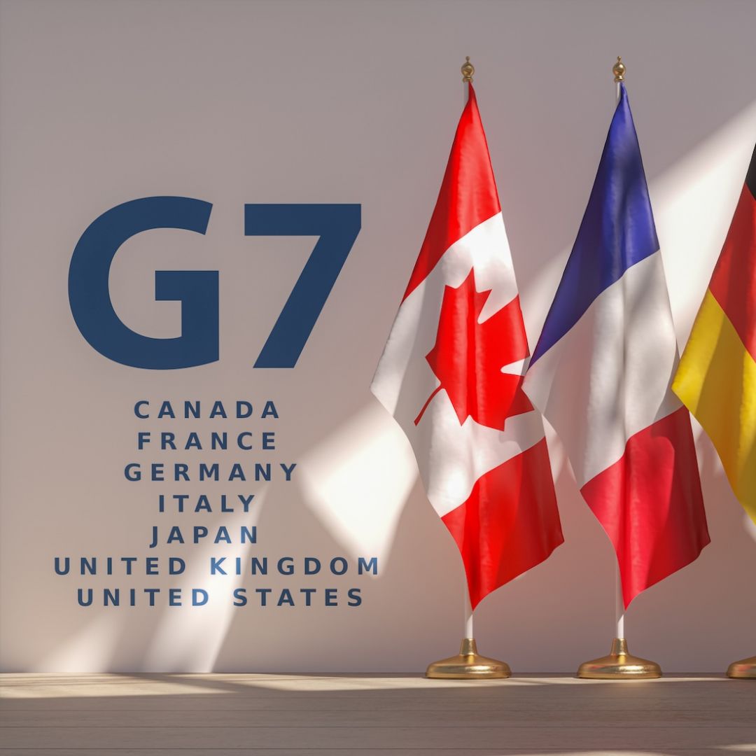 An image shows a row of flags from the G7 members. 