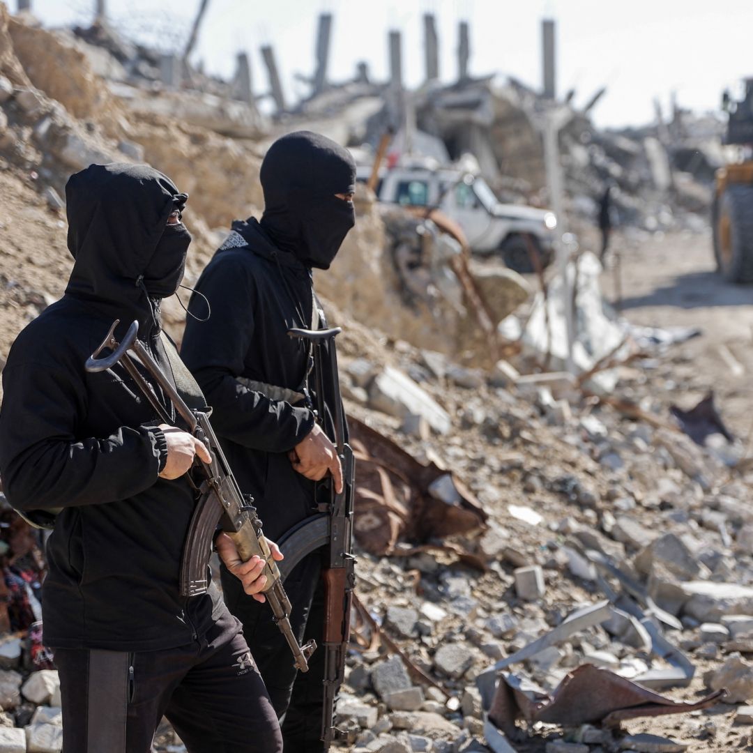 Palestinian Hamas militants stand guard as Egyptian and Red Cross workers search for the bodies of the last two remaining hostages from under the rubble of the Jabalia refugee camp, in the northern Gaza Strip, on Dec. 1, 2025.