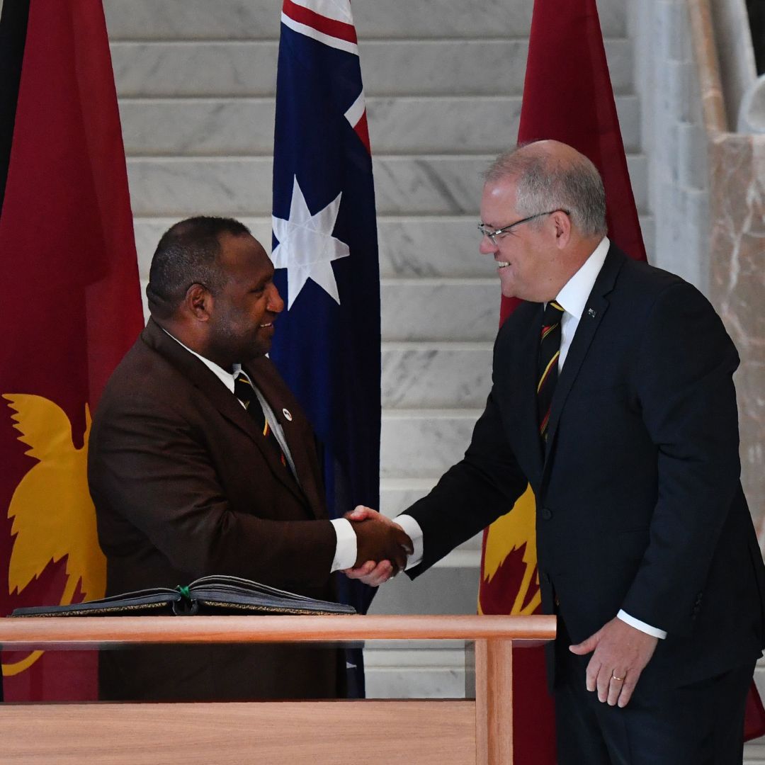 Papua New Guinea's Prime Minister James Marape (left) shakes hands with Australia's Prime Minister Scott Morrison as their wives look on in Canberra during July.