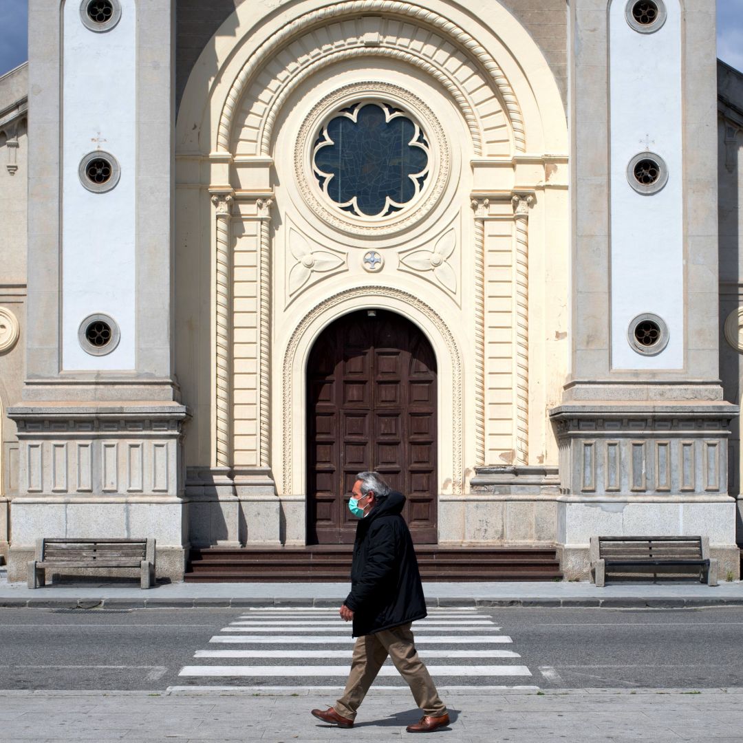 A man wearing a protective mask walks in the empty square in front of a cathedral in Locri, Italy, on April 7, 2020. 