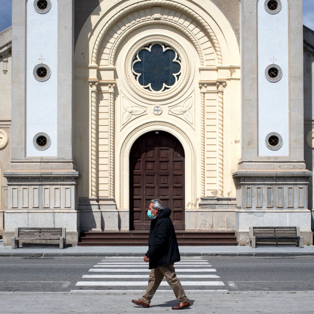 A man wearing a protective mask in Locri, Italy. A man wearing a protective mask walks in the empty square in front of a cathedral in Locri, Italy, on April 7, 2020.