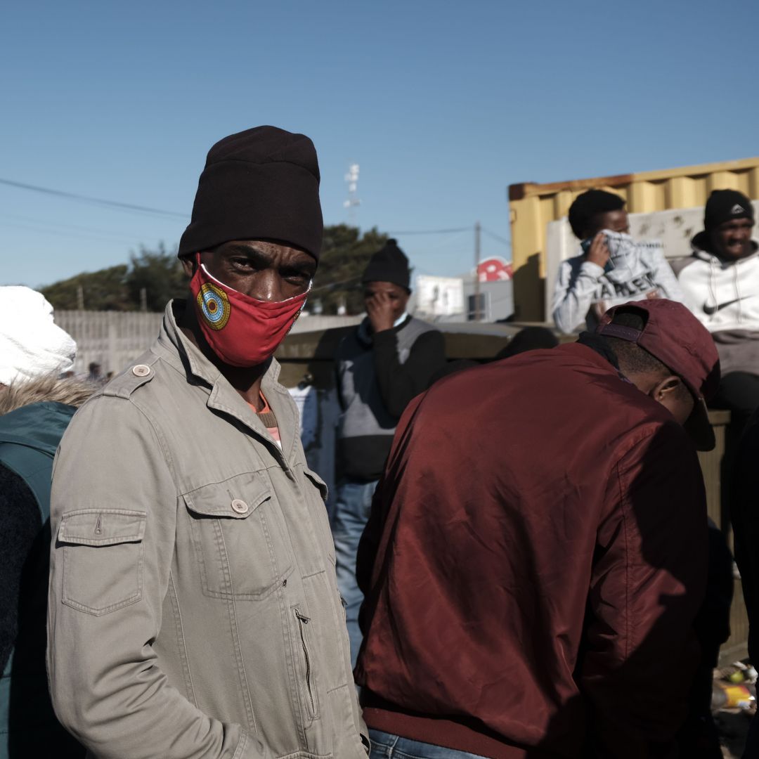 People stand in line to receive grant payments from the South African Social Security Agency (SASSA) in Khayelitsha, a township located near Cape Town, on May 4, 2020. 