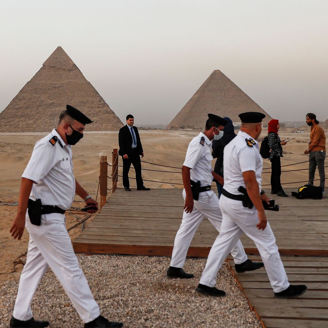 Policemen walk near an overlook at the Giza Pyramids in Egypt ahead of a ceremony commemorating the launch of the site's first environmentally-friendly bus and restaurant on Oct. 20, 2020. 