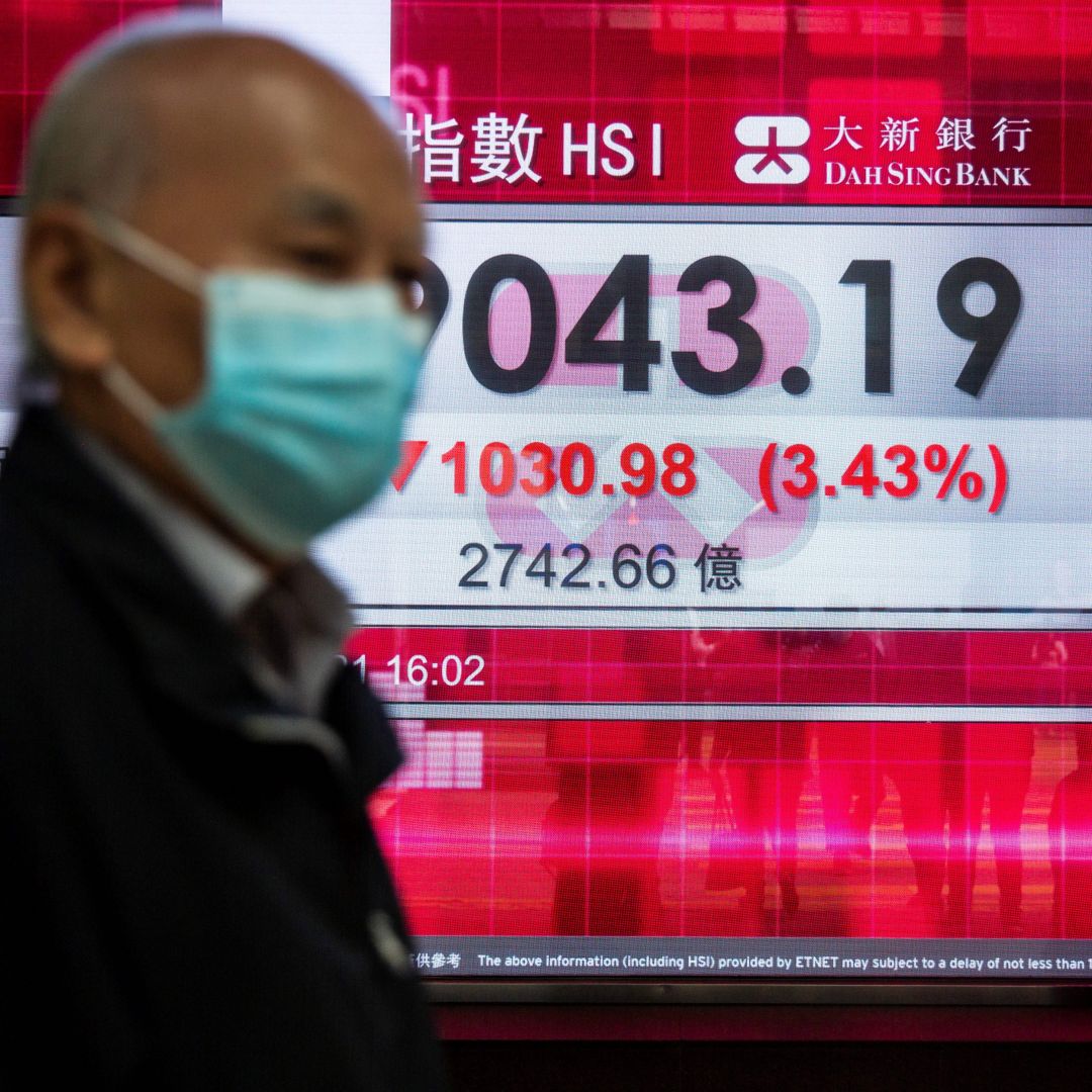 People walk past an electronic display showing Hong Kong’s Hang Seng Index in the city’s central district on Feb. 26, 2021. 