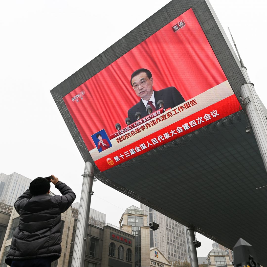 A man in Beijing, China, uses his mobile phone to take a picture of a big screen showing Chinese Premier Li Keqiang delivering a speech at the opening session of the National People's Congress (NPC) on March 5, 2021. A man in Beijing, China, uses his mobile phone to take a picture of a big screen showing Chinese Premier Li Keqiang delivering a speech at the opening session of the National People's Congress (NPC) on March 5, 2021.